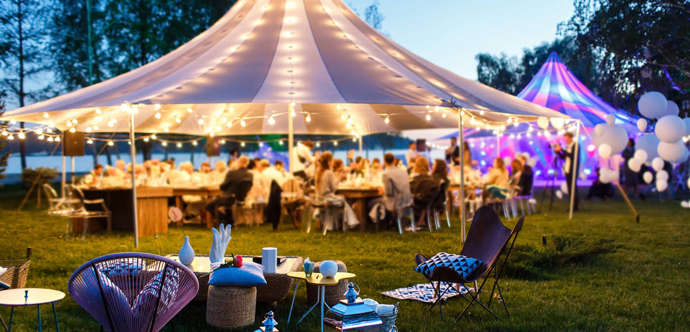 An outdoor gathering full of people and two large tents