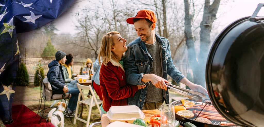 A couple hugging and smiling at each other while the man grills outside