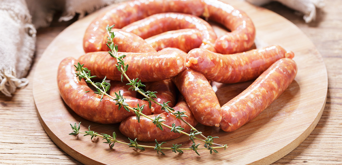 Raw sausage displayed with a rosemary garnish